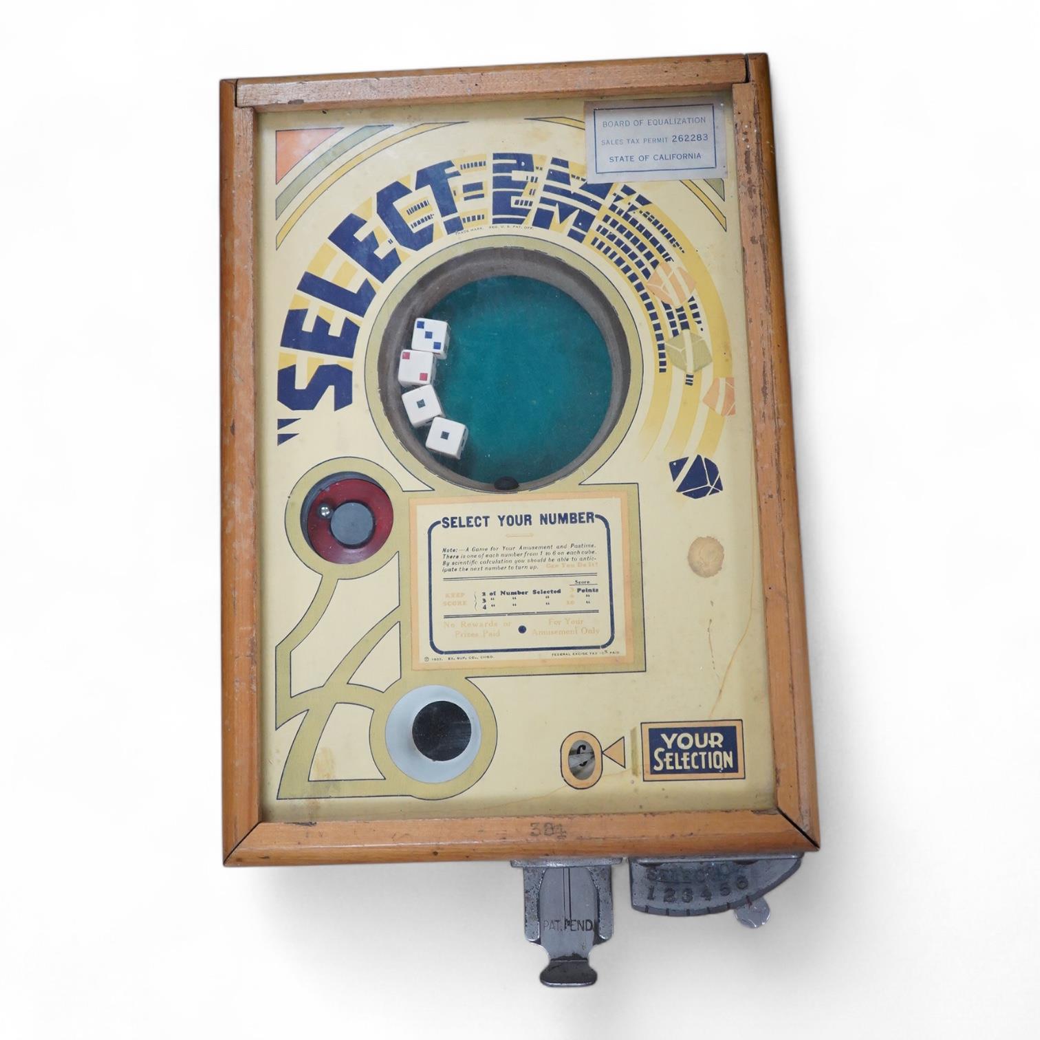 A ‘Select-Em’ table top pinball style dice game in a teak frame dated 1933, with Board of Equalization sales tax permit label for the State of California, 26cm wide, 35.5cm deep, 12.5cm high